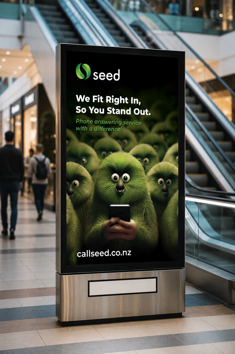 A Seed digital screen inside a shopping centre beside the escalators, reading We Fit Right In, So You Stand Out