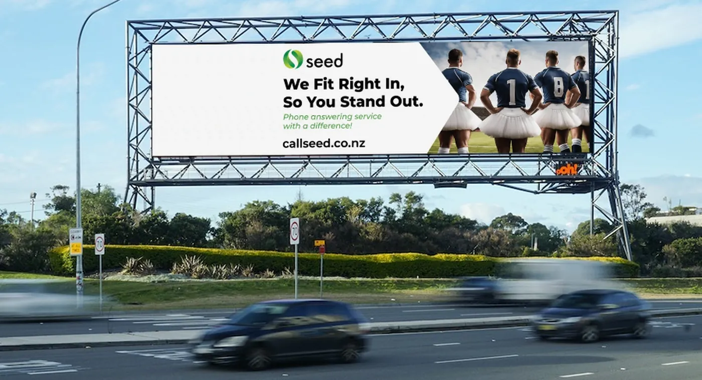 A Seed billboard on a Sydney airport-approach road reading We Fit Right In, So You Stand Out