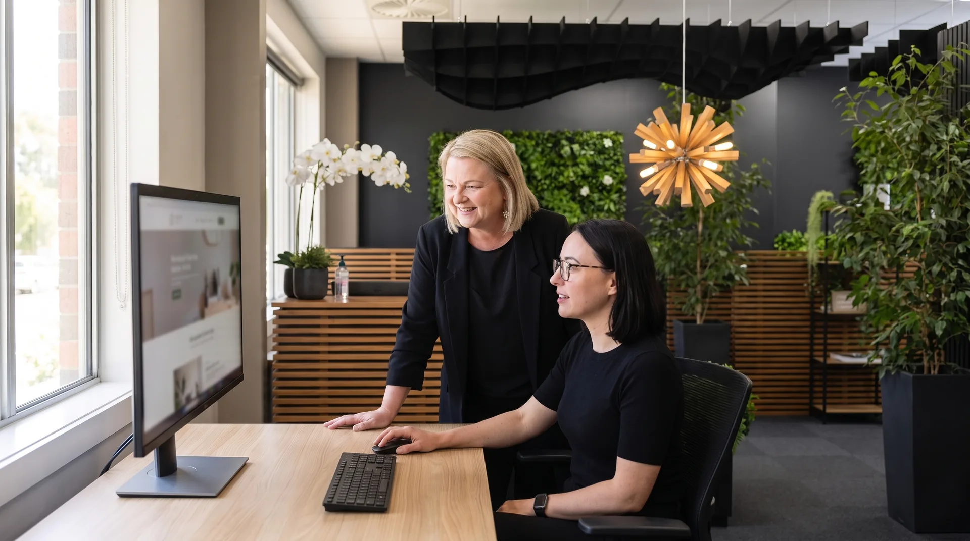 Two of the Seed team reviewing a client website on a desktop monitor in the Seed office
